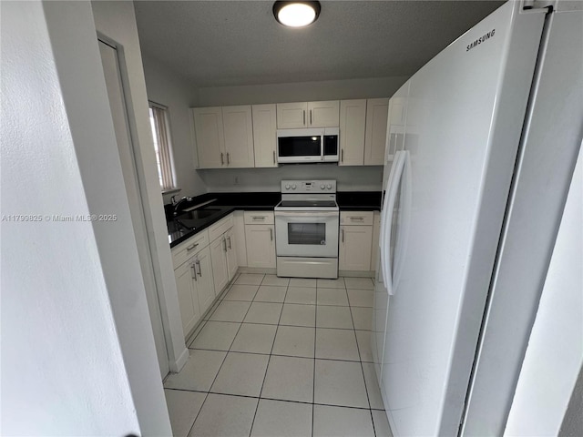 2710 W 76th St Unit 103, Hialeah, FL 33016 - kitchen featuring white appliances, dark countertops, light tile patterned floors, and white cabinets