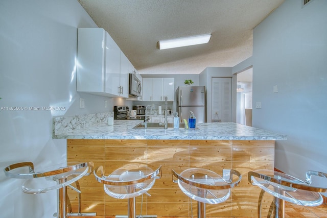 6755 NW 199th St, Hialeah, FL 33015 - kitchen featuring appliances with stainless steel finishes, a peninsula, light countertops, white cabinets, and a sink