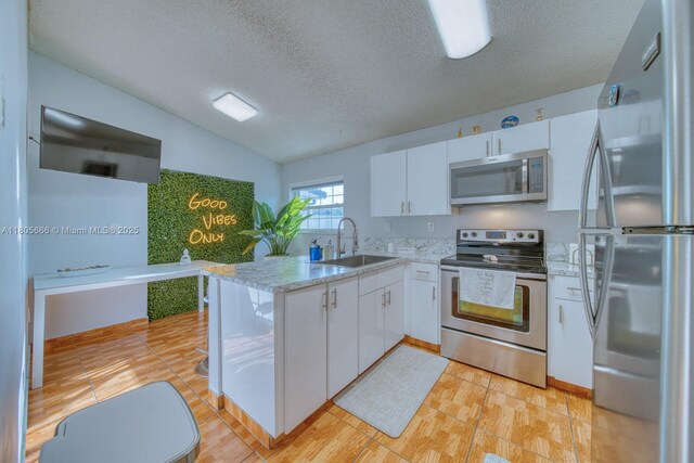 6755 NW 199th St, Hialeah, FL 33015 - kitchen featuring appliances with stainless steel finishes, a sink, white cabinets, a textured ceiling, and lofted ceiling