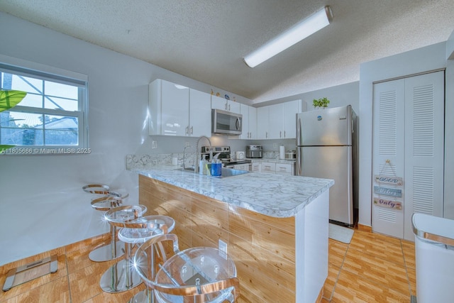 6755 NW 199th St, Hialeah, FL 33015 - kitchen featuring appliances with stainless steel finishes, light countertops, a peninsula, white cabinets, and a textured ceiling