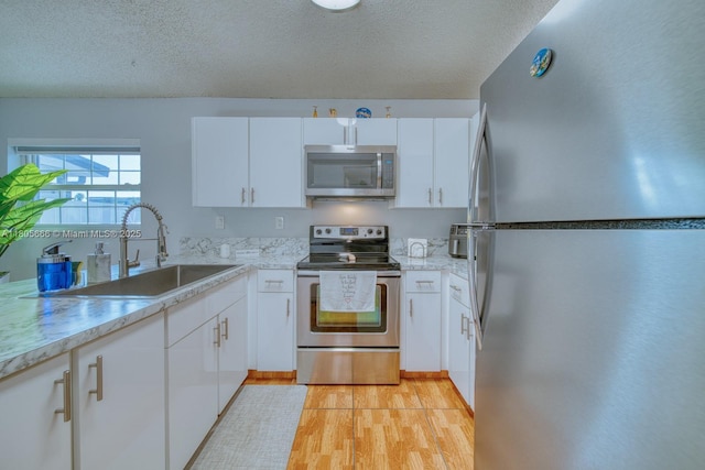 6755 NW 199th St, Hialeah, FL 33015 - kitchen featuring appliances with stainless steel finishes, a sink, light wood-style floors, light countertops, and white cabinets
