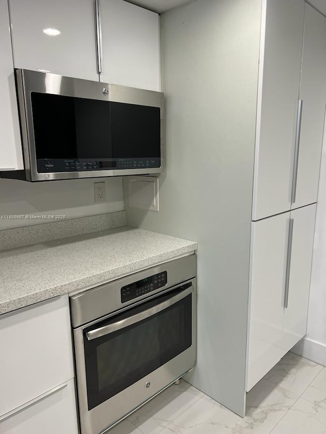 7601 E Treasure Dr Unit 1622, North Bay Village, FL 33141 - kitchen view of appliances with stainless steel finishes, white cabinetry, modern cabinets, and light stone counters