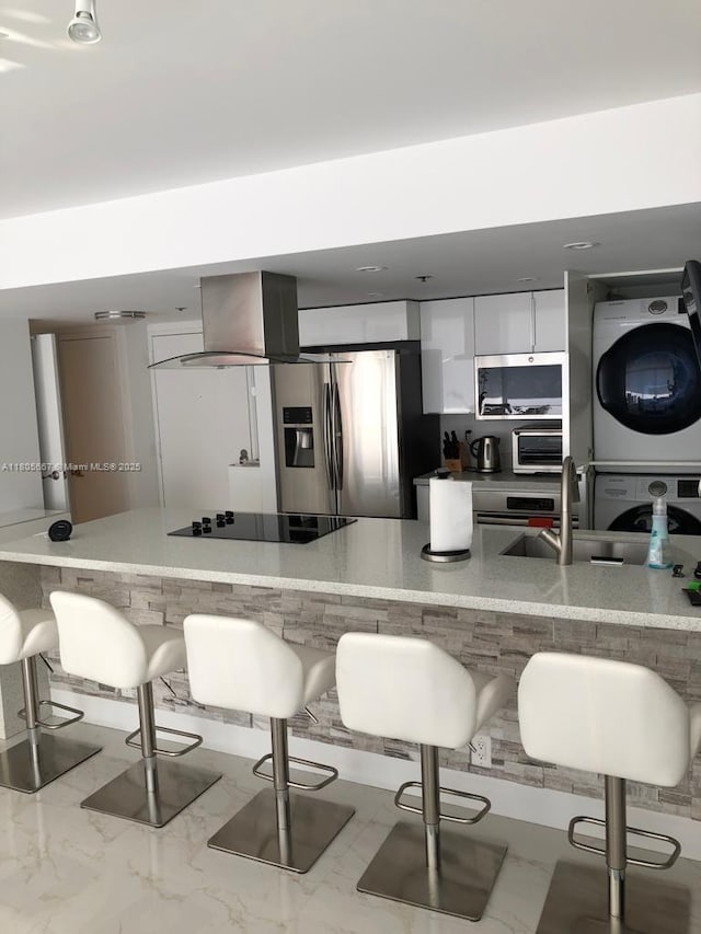 7601 E Treasure Dr Unit 1622, North Bay Village, FL 33141 - kitchen with stacked washer / drying machine, appliances with stainless steel finishes, a sink, a breakfast bar, and white cabinets