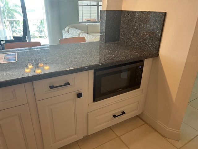 400 Diplomat Pkwy Unit 611, Hallandale Beach, FL 33009 - kitchen with black microwave, light tile patterned floors, white cabinetry, and dark stone counters