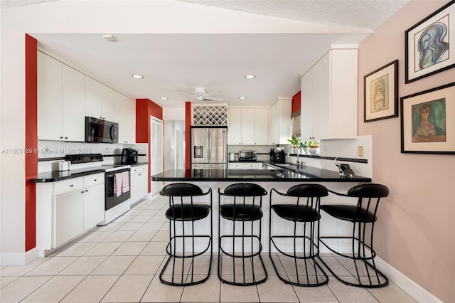 8610 SW 83rd St, Miami, FL 33143 - kitchen with electric range, stainless steel fridge, a sink, dark countertops, and a peninsula