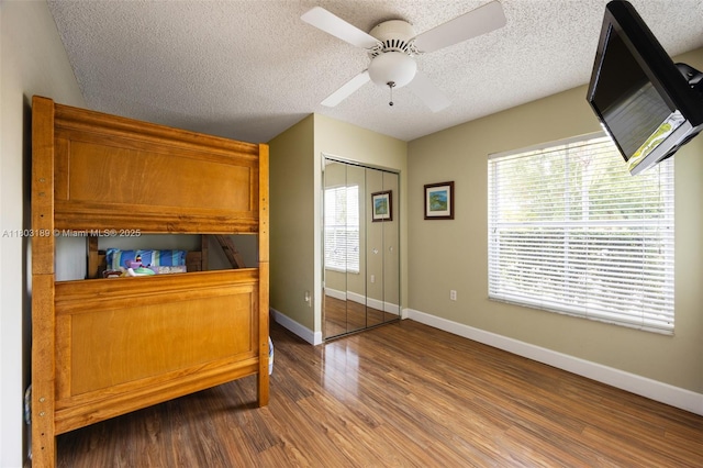 8610 SW 83rd St, Miami, FL 33143 - bedroom featuring wood finished floors, a textured ceiling, baseboards, a closet, and a ceiling fan