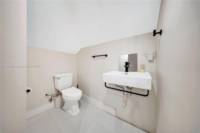 7411 Carlyle Ave, Miami Beach, FL 33141 - bathroom featuring baseboards, a sink, toilet, vaulted ceiling, and tile patterned floors