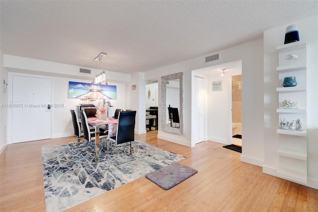 1500 S Ocean Dr Unit 7J, Hollywood, FL 33019 - dining space with a textured ceiling, built in shelves, light wood finished floors, baseboards, and a chandelier