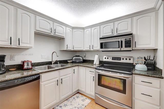 1500 S Ocean Dr Unit 7J, Hollywood, FL 33019 - kitchen featuring appliances with stainless steel finishes, a sink, dark countertops, light wood-style flooring, and white cabinets