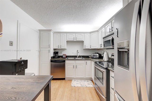 1500 S Ocean Dr Unit 7J, Hollywood, FL 33019 - kitchen featuring appliances with stainless steel finishes, a sink, light wood-type flooring, a textured ceiling, and white cabinetry