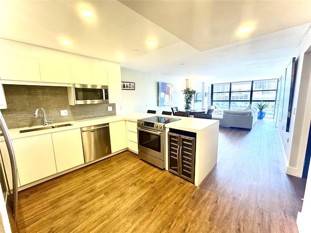 200 Leslie Dr Unit 817, Hallandale Beach, FL 33009 - kitchen featuring stainless steel appliances, a sink, a peninsula, wine cooler, and wood finished floors