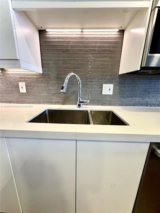 200 Leslie Dr Unit 817, Hallandale Beach, FL 33009 - kitchen featuring a sink, light countertops, white cabinetry, and decorative backsplash