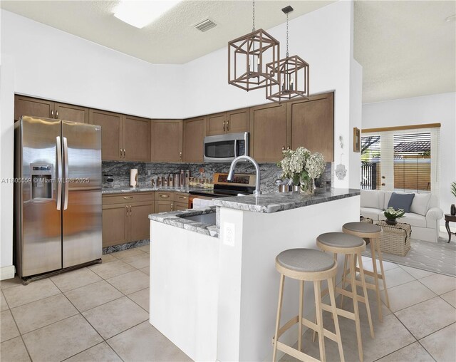 9029 SW 214th St, Cutler Bay, FL 33189 - kitchen with stainless steel appliances, light tile patterned floors, tasteful backsplash, a peninsula, and a high ceiling
