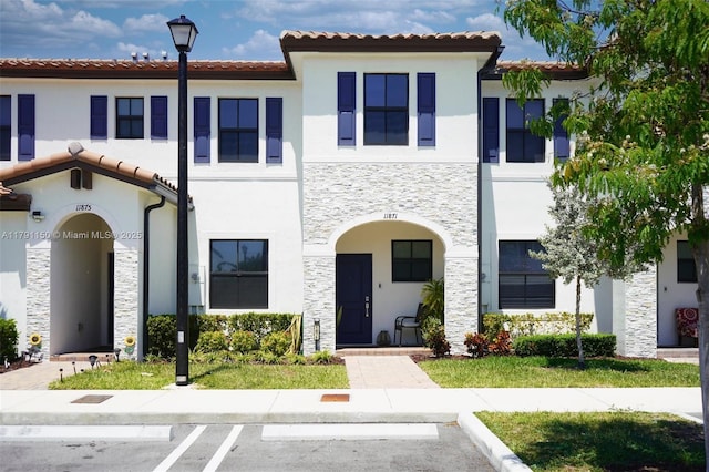 11871 SW 247th Ter, Homestead, FL 33032 - view of front facade with stone siding, stucco siding, a tile roof, and uncovered parking