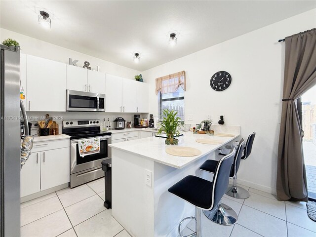 11871 SW 247th Ter, Homestead, FL 33032 - kitchen featuring stainless steel appliances, light countertops, a kitchen breakfast bar, and light tile patterned floors