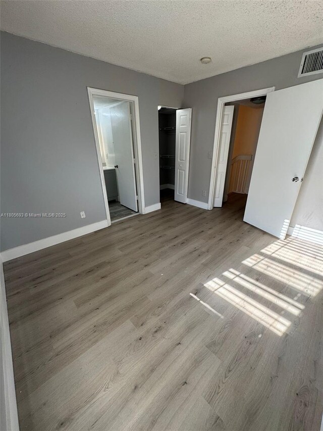 12605 SW 54th Ct Unit 12605, Miramar, FL 33027 - unfurnished bedroom featuring wood finished floors, baseboards, a textured ceiling, a closet, and ensuite bathroom