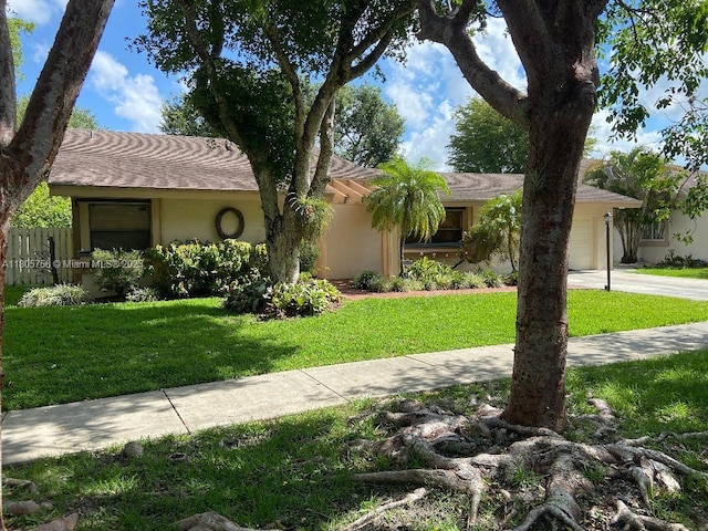 view of front of house with stucco siding, a front lawn, an attached garage, and driveway