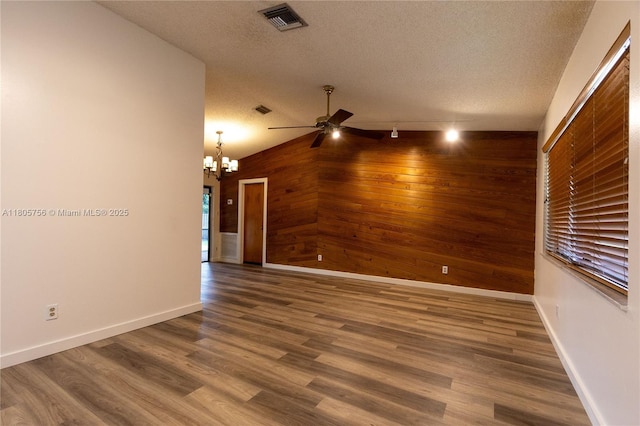 spare room with wooden walls, ceiling fan, a textured ceiling, a chandelier, and baseboards