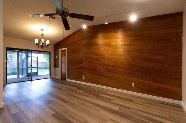 unfurnished room featuring wooden walls, a ceiling fan, baseboards, a chandelier, and lofted ceiling