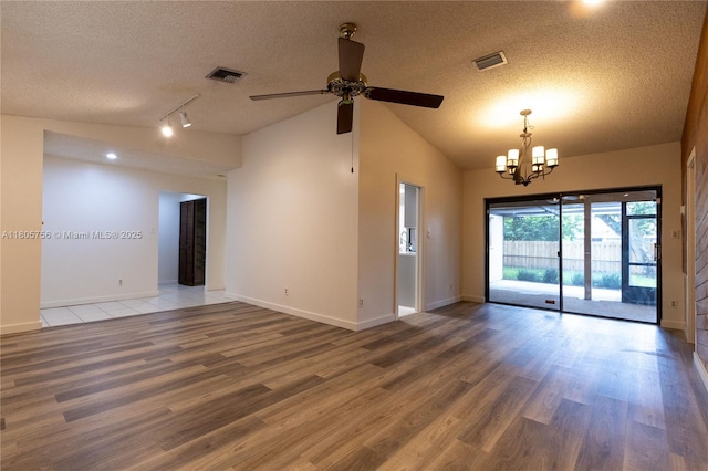 empty room with a textured ceiling, a ceiling fan, vaulted ceiling, wood finished floors, and a chandelier