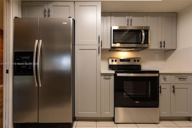 kitchen with appliances with stainless steel finishes, light countertops, gray cabinetry, and light tile patterned floors
