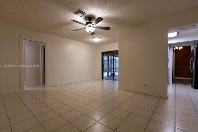 empty room featuring a textured ceiling, a ceiling fan, light tile patterned flooring, and baseboards