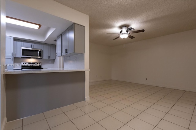 kitchen featuring appliances with stainless steel finishes, light countertops, gray cabinetry, a ceiling fan, and a textured ceiling
