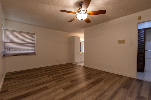 empty room featuring ceiling fan, wood finished floors, a textured ceiling, and baseboards