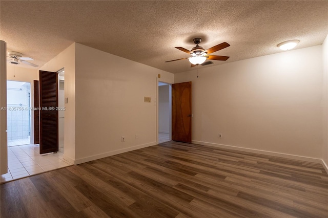 spare room featuring a ceiling fan, wood finished floors, a textured ceiling, and baseboards