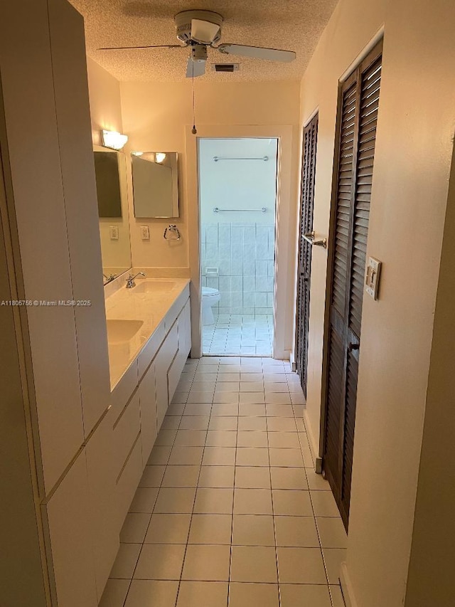 bathroom featuring a textured ceiling, toilet, tile patterned flooring, ceiling fan, and double vanity