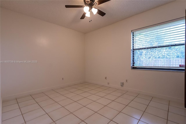 spare room featuring ceiling fan, light tile patterned flooring, baseboards, and a textured ceiling
