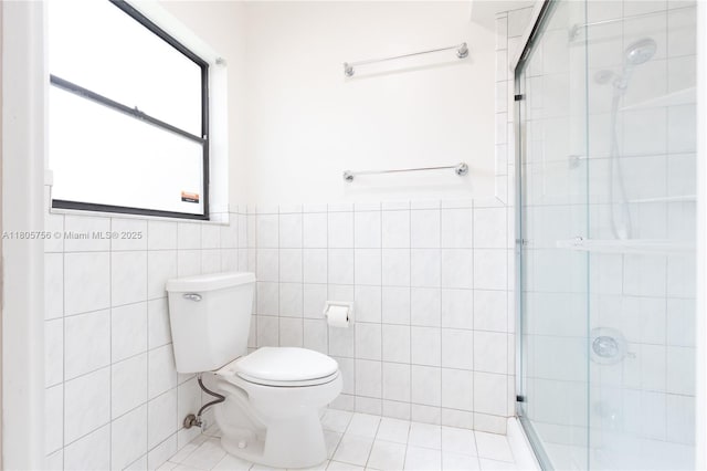 bathroom featuring a shower stall, tile walls, toilet, tile patterned flooring, and a wainscoted wall
