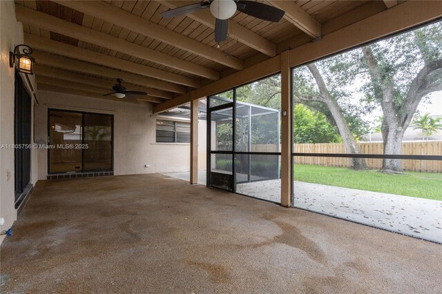unfurnished sunroom featuring ceiling fan, beam ceiling, and healthy amount of natural light