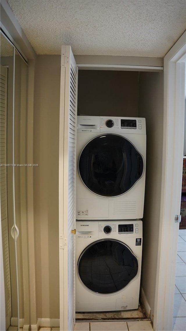 8810 SW 132nd Pl Unit 303Dn, Miami, FL 33186 - laundry room with stacked washing machine and dryer, tile patterned flooring, a textured ceiling, and baseboards