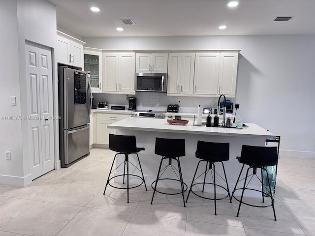 kitchen featuring stainless steel appliances, light countertops, a breakfast bar, backsplash, and baseboards
