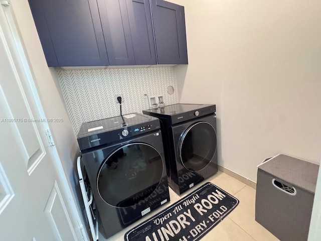 laundry area featuring washing machine and dryer, cabinet space, light tile patterned floors, and baseboards