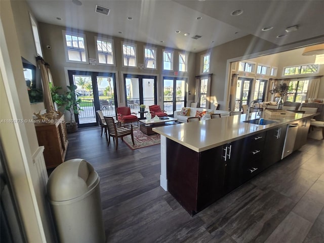 kitchen with open floor plan, a sink, light countertops, a towering ceiling, and a spacious island