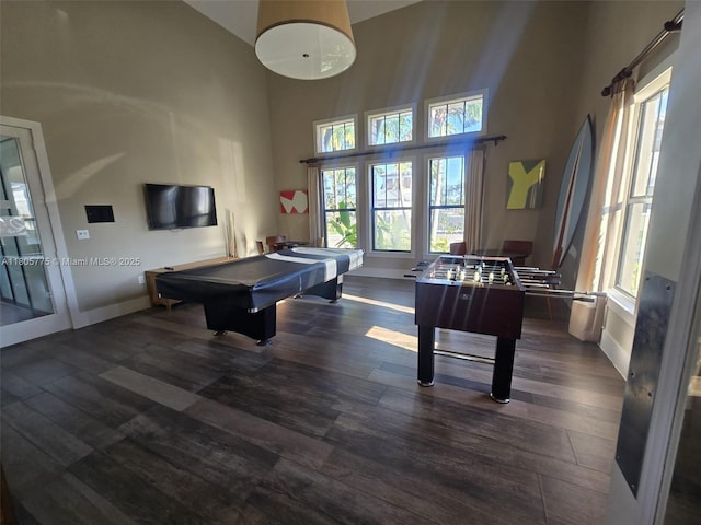game room with a towering ceiling, pool table, wood finished floors, and baseboards