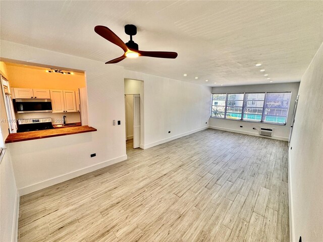 4710 Pine Tree Dr Unit 31, Miami Beach, FL 33140 - unfurnished living room with light wood-style flooring, ceiling fan, baseboards, recessed lighting, and an AC wall unit