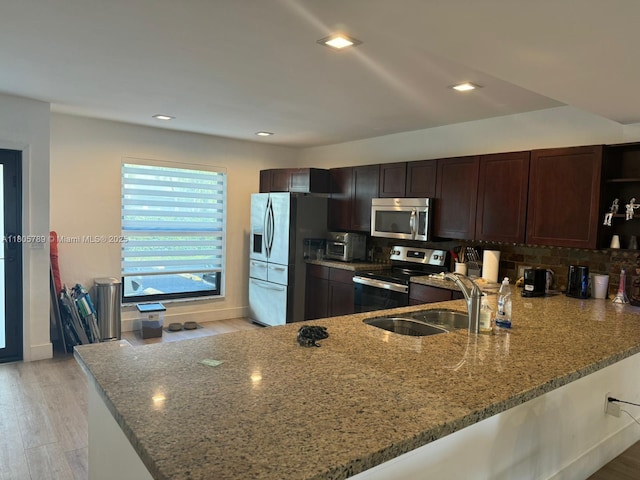3720 NE 167th St Unit 39, North Miami Beach, FL 33160 - kitchen with stainless steel appliances, a peninsula, light stone counters, dark brown cabinets, and tasteful backsplash