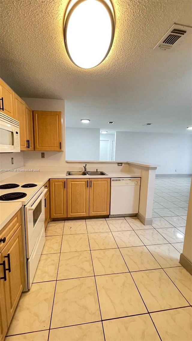 kitchen with white appliances, a sink, light countertops, a textured ceiling, and a peninsula