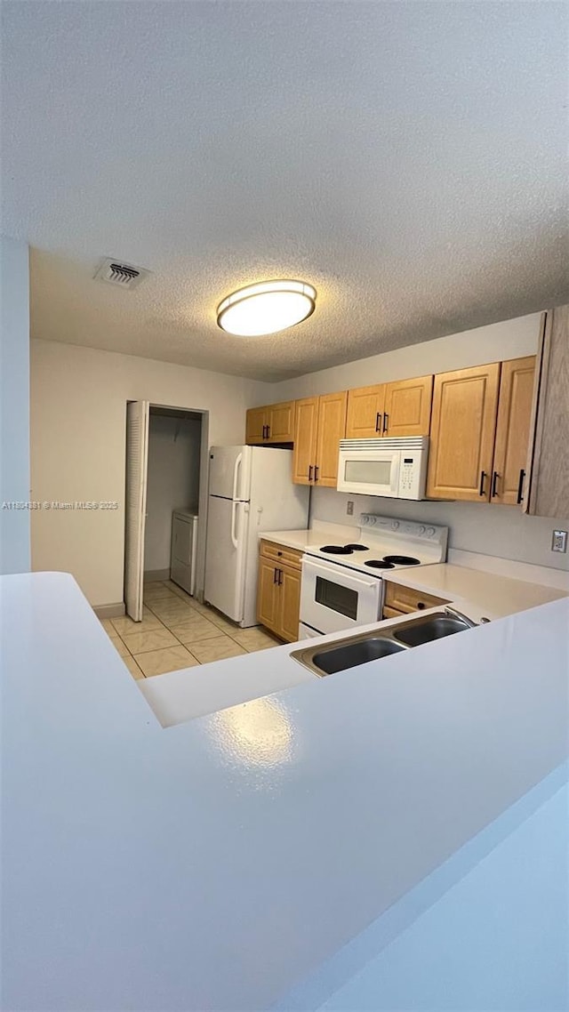 kitchen featuring white appliances, washing machine and dryer, light countertops, a textured ceiling, and a sink