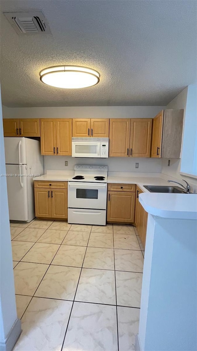 kitchen featuring white appliances, light countertops, a textured ceiling, a sink, and light brown cabinets