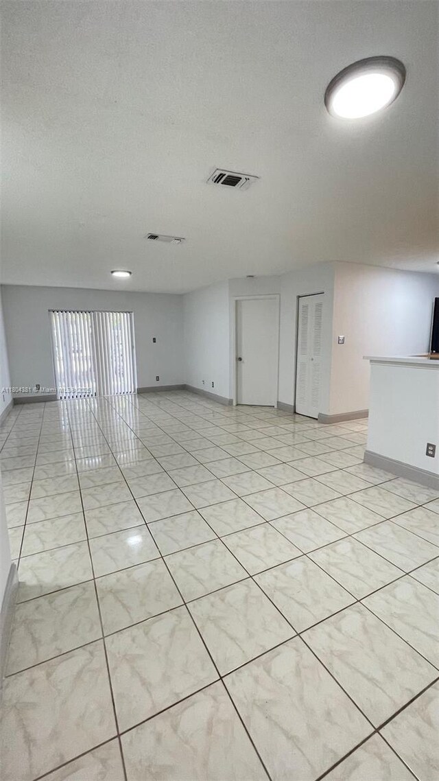 unfurnished room with baseboards, a textured ceiling, and light tile patterned floors