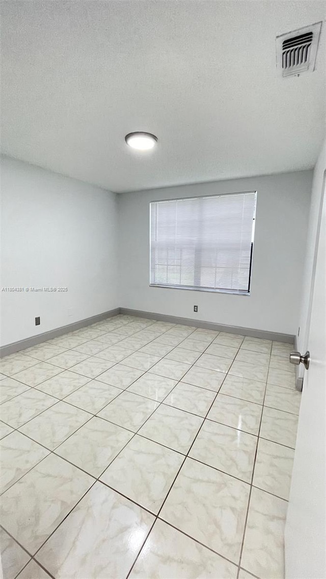 empty room featuring a textured ceiling and baseboards