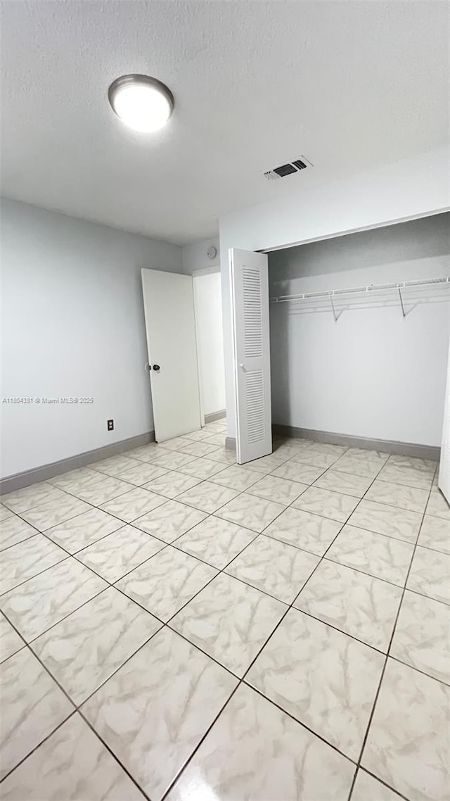 unfurnished bedroom with a closet, a textured ceiling, and baseboards