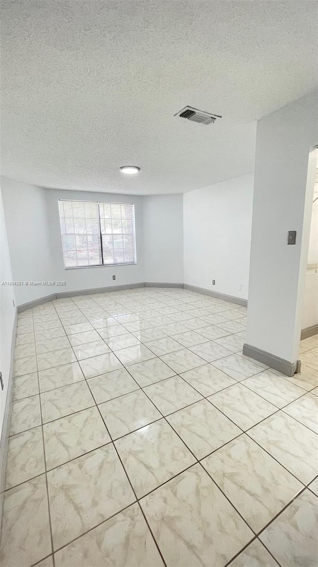 empty room featuring a textured ceiling and baseboards