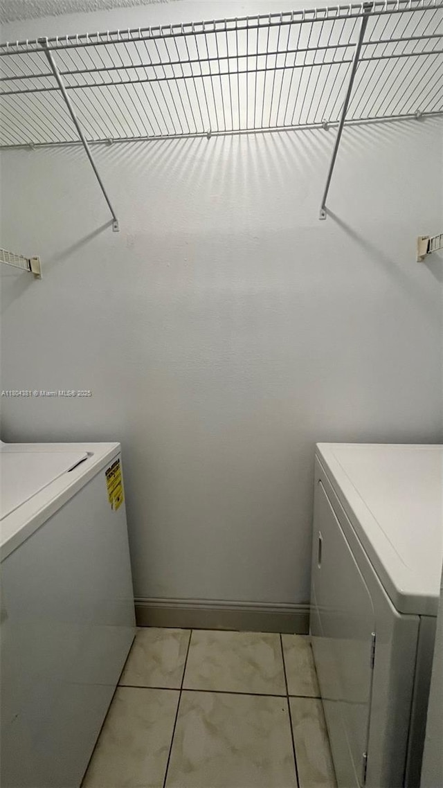 laundry room featuring washer / dryer, light tile patterned floors, and baseboards