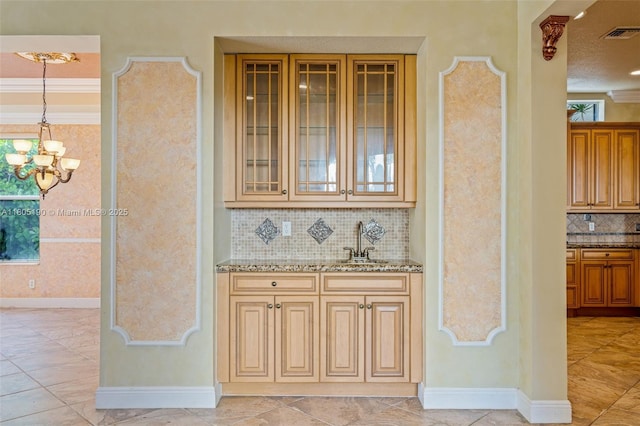 9192 Nugent Trl, West Palm Beach, FL 33411 - bar area featuring a chandelier, decorative backsplash, a sink, baseboards, and hanging light fixtures