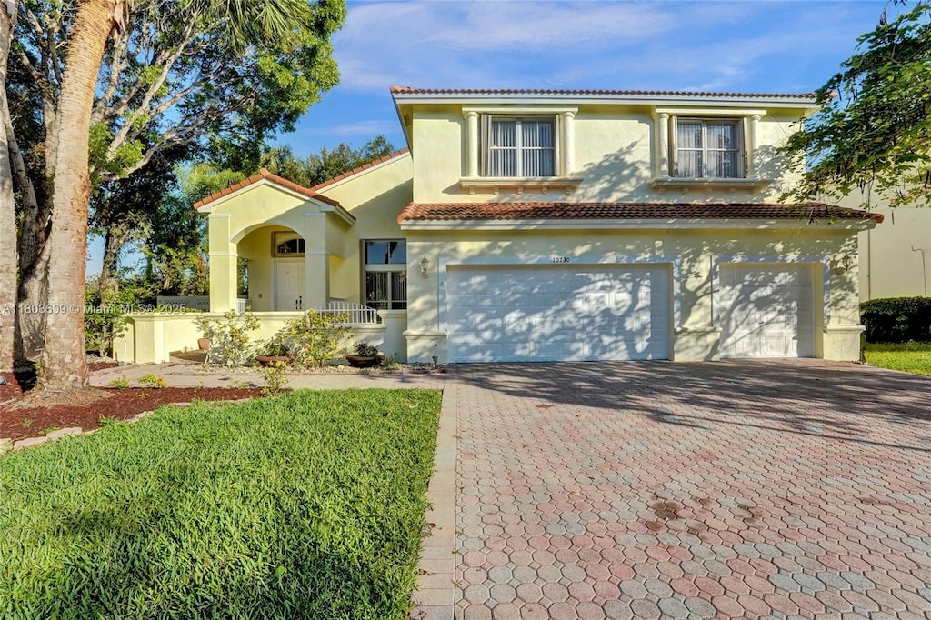 mediterranean / spanish home with decorative driveway, stucco siding, an attached garage, and a tiled roof